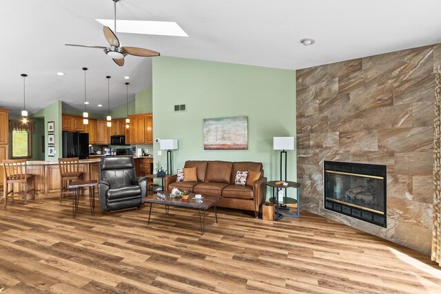 living area featuring light wood-style floors, ceiling fan, visible vents, and high vaulted ceiling