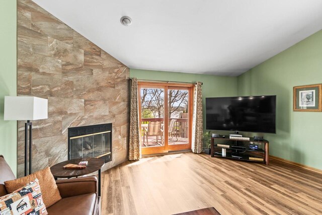living room featuring a fireplace, wood finished floors, and lofted ceiling