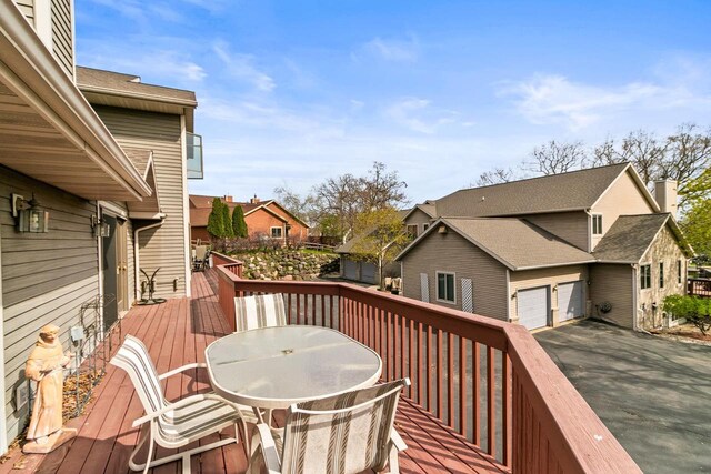 wooden terrace featuring a residential view, outdoor dining area, and a garage