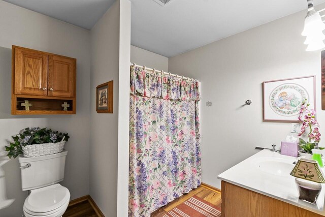 bathroom featuring vanity, curtained shower, toilet, and wood finished floors