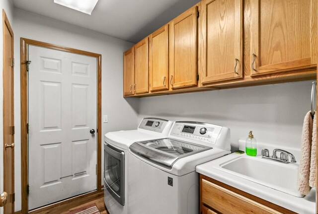 clothes washing area featuring a sink, cabinet space, and washer and clothes dryer
