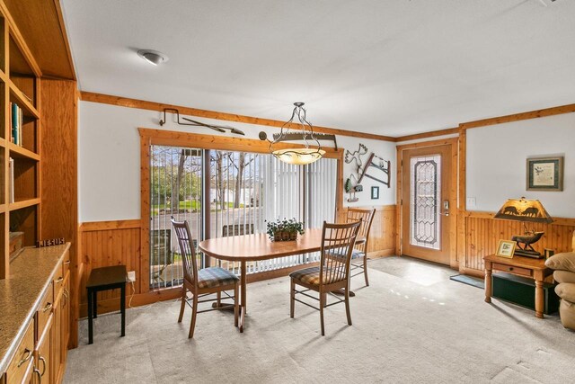 dining space with light colored carpet, wood walls, and wainscoting