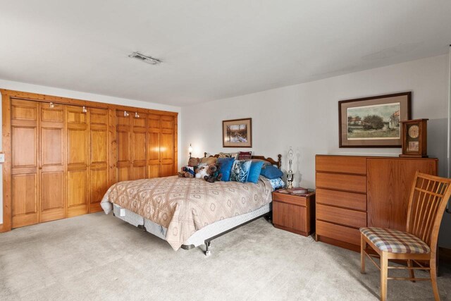 bedroom featuring light colored carpet, visible vents, and a closet