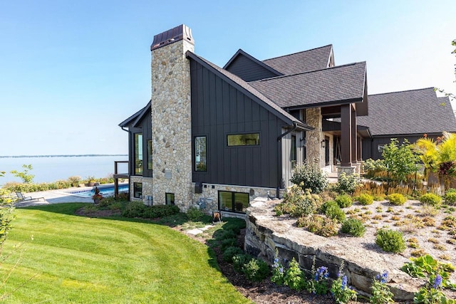 9458 Warner Rd, Winneconne, WI 54986 - view of side of property with board and batten siding, roof with shingles, a lawn, and stone siding