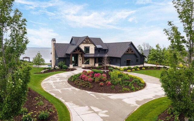 9458 Warner Rd, Winneconne, WI 54986 - view of front of house featuring curved driveway, a standing seam roof, a water view, a metal roof, and a front lawn