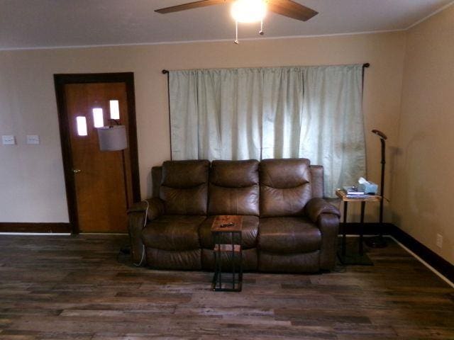 living area featuring crown molding, wood finished floors, a ceiling fan, and baseboards