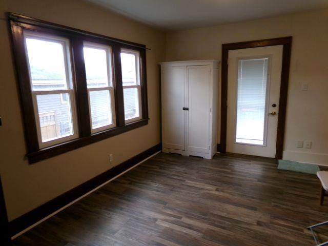 unfurnished bedroom with baseboards and dark wood-style flooring