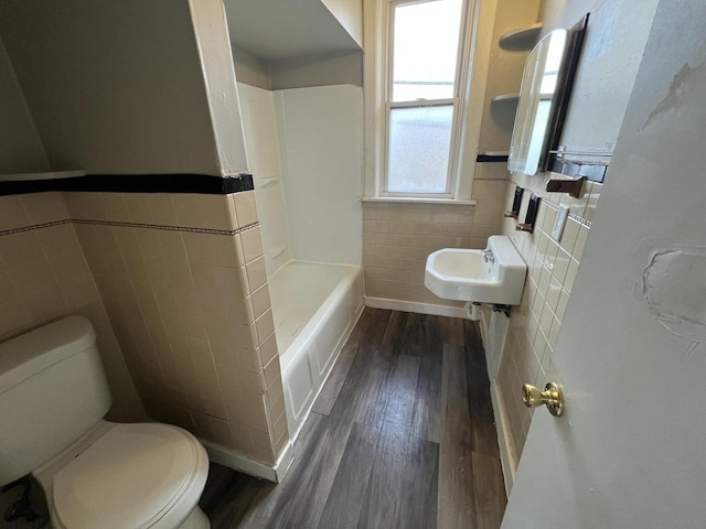 bathroom with tile walls, toilet, wood finished floors, and wainscoting