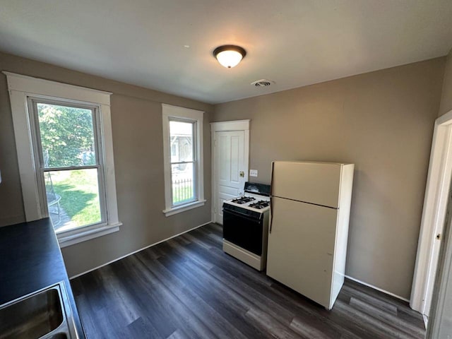kitchen featuring visible vents, white appliances, and dark wood-style floors