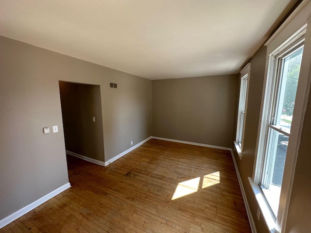 unfurnished room featuring baseboards, visible vents, and hardwood / wood-style flooring
