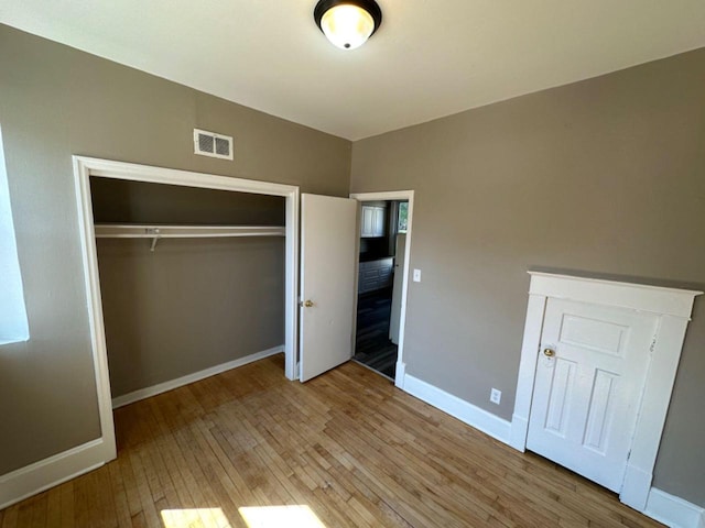unfurnished bedroom with light wood-type flooring, baseboards, visible vents, and a closet