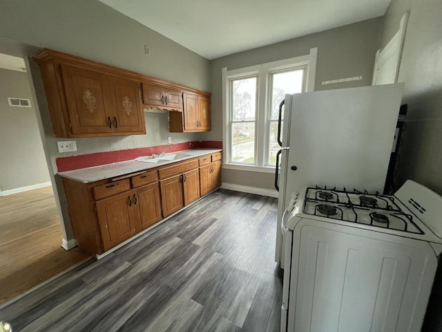 kitchen with visible vents, baseboards, white appliances, and a sink