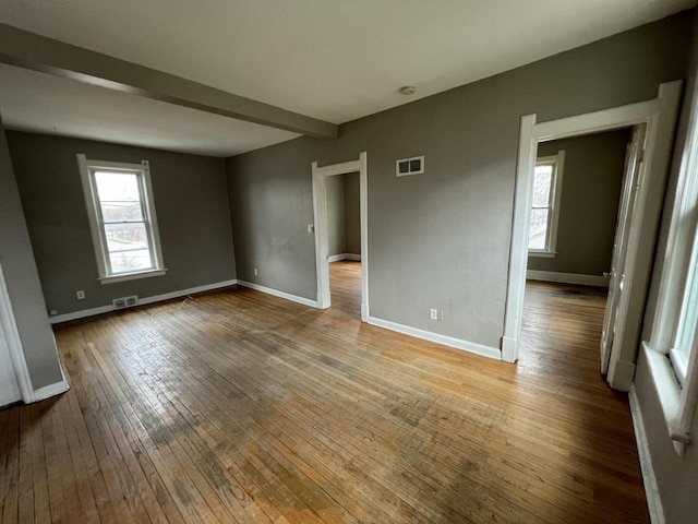 spare room featuring hardwood / wood-style floors, a wealth of natural light, baseboards, and visible vents