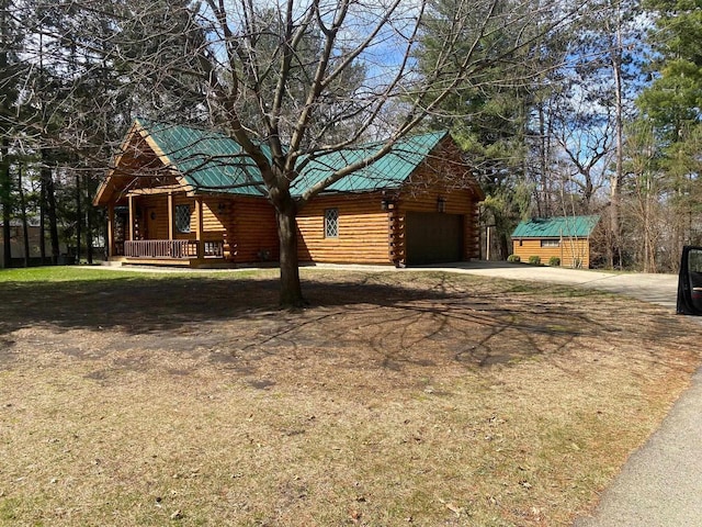 N7589 Lakeside Dr, Portage, WI 53901 - log cabin featuring log siding, an attached garage, driveway, covered porch, and metal roof