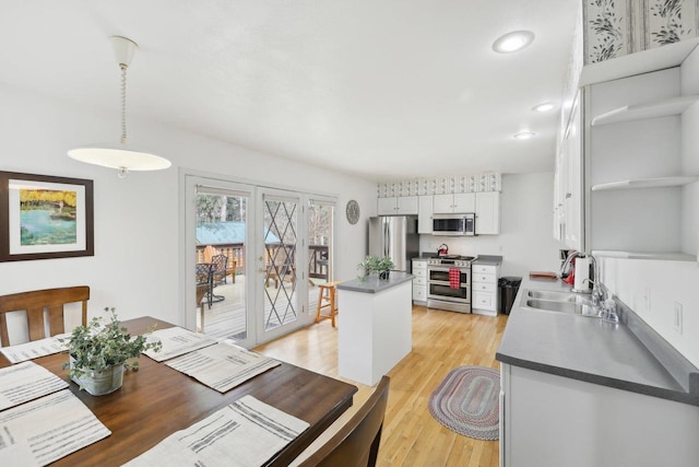 N7589 Lakeside Dr, Portage, WI 53901 - kitchen featuring a sink, light wood-style floors, pendant lighting, white cabinets, and appliances with stainless steel finishes