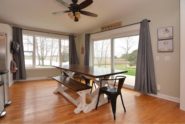 dining space with lofted ceiling, visible vents, light wood finished floors, a ceiling fan, and baseboards