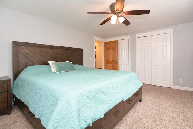 bedroom featuring light carpet, baseboards, a ceiling fan, and multiple closets
