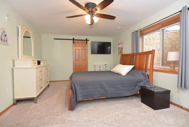 bedroom featuring baseboards, ceiling fan, a barn door, and light colored carpet