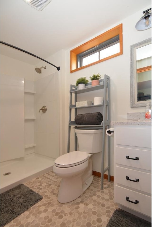 bathroom with toilet, baseboards, walk in shower, visible vents, and vanity