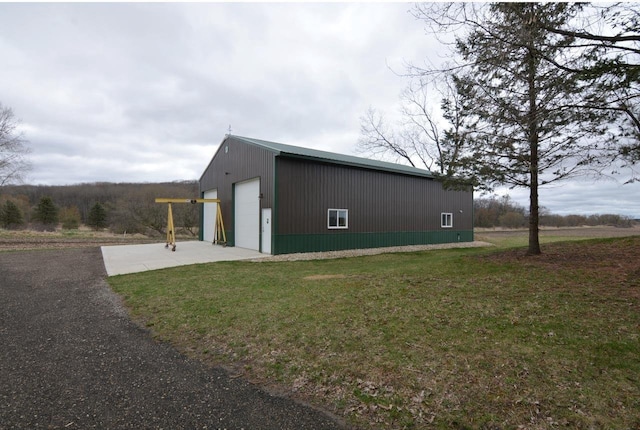 view of side of property with a yard, an outdoor structure, driveway, and a detached garage
