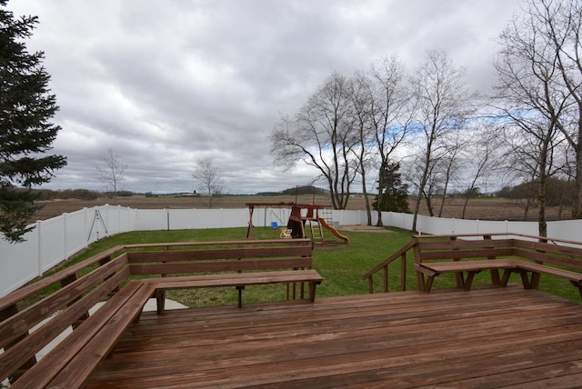 deck with a playground, a lawn, and a fenced backyard