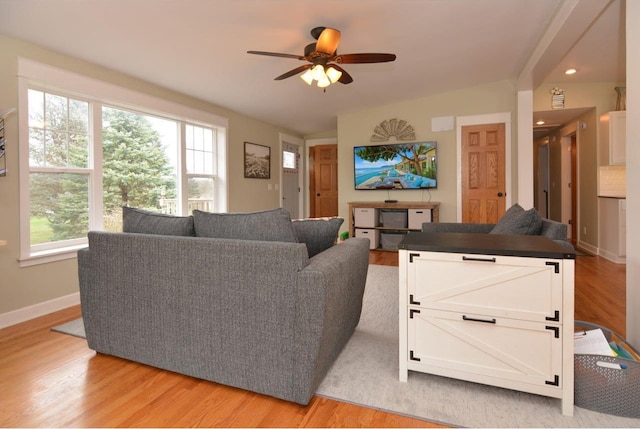 living room with baseboards, light wood-style flooring, and a ceiling fan