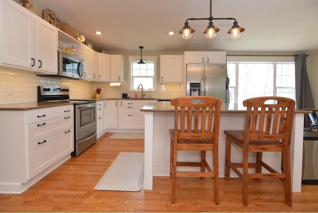 kitchen with white cabinetry, stainless steel appliances, open shelves, and decorative backsplash