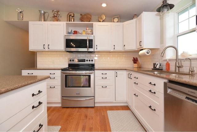 kitchen with white cabinetry, stainless steel appliances, tasteful backsplash, and a sink