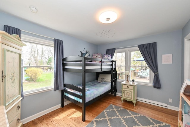 bedroom with baseboards, wood finished floors, and a baseboard radiator