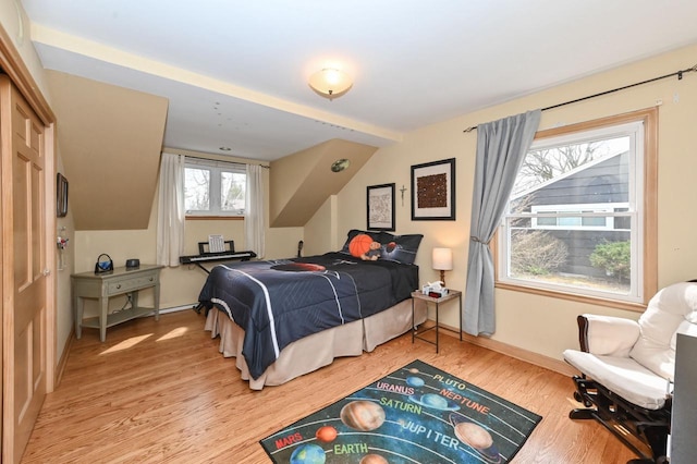 bedroom featuring light wood-type flooring, vaulted ceiling, and baseboards