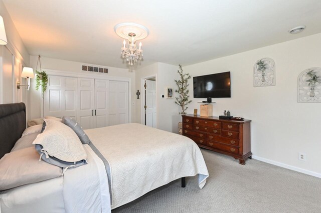bedroom featuring a closet, light carpet, baseboards, visible vents, and a notable chandelier