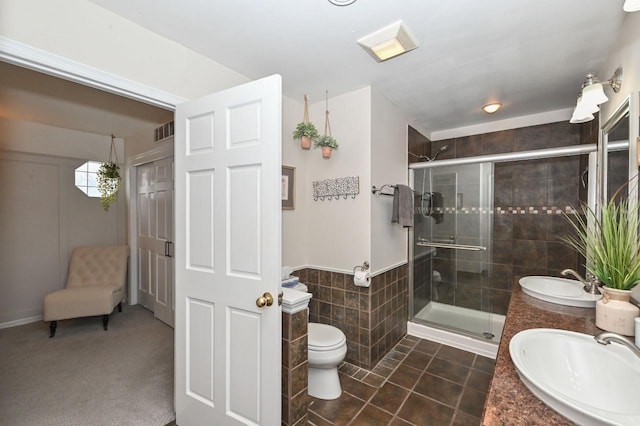 full bathroom featuring tile walls, visible vents, a shower stall, and a sink
