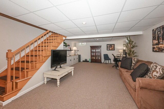 carpeted living area with baseboards, stairs, and a drop ceiling