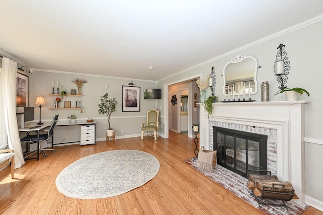 living room featuring crown molding, baseboards, wood finished floors, and a fireplace