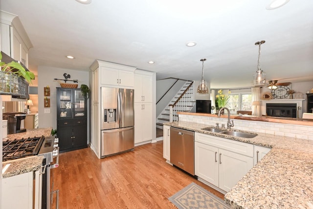 kitchen featuring a sink, a ceiling fan, white cabinetry, hanging light fixtures, and appliances with stainless steel finishes