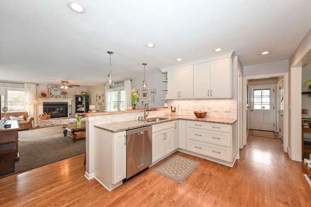 kitchen featuring plenty of natural light, stainless steel dishwasher, a peninsula, and a sink