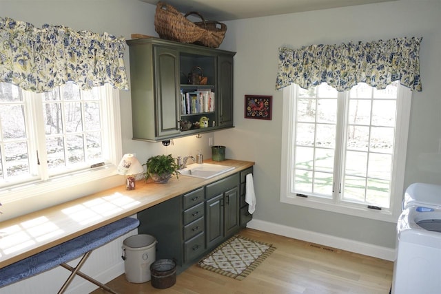 interior space with baseboards, washer / clothes dryer, visible vents, and light wood-style flooring