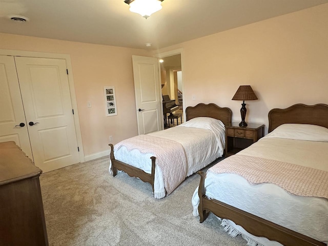 bedroom featuring baseboards, visible vents, a closet, and light colored carpet
