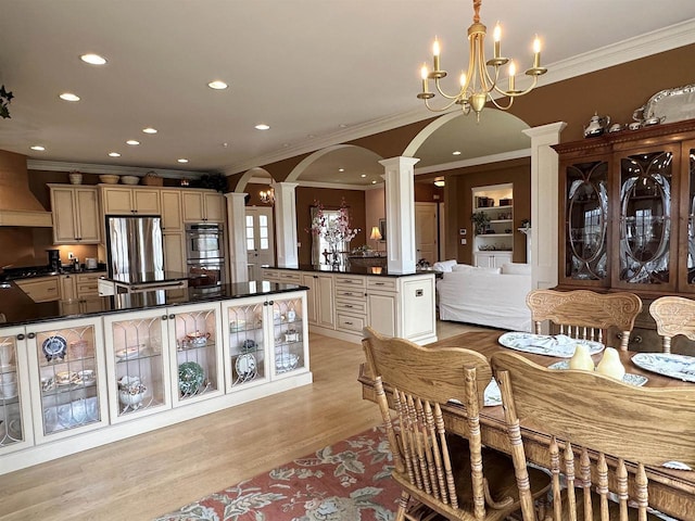 dining space with arched walkways, recessed lighting, light wood-style floors, ornate columns, and crown molding