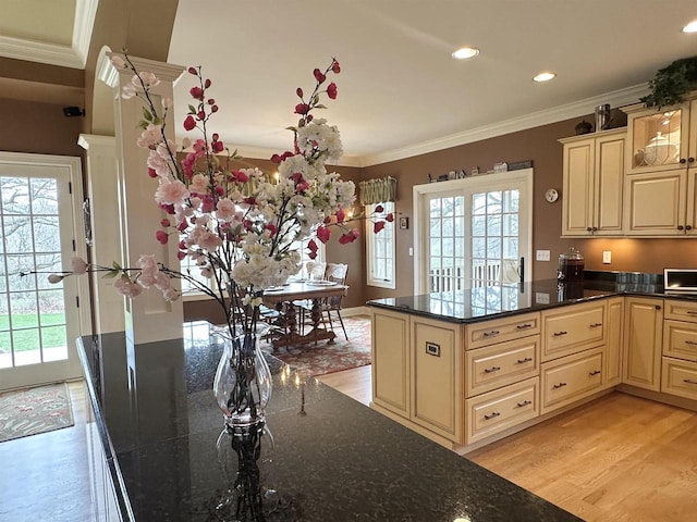 kitchen featuring dark stone countertops, light wood-type flooring, cream cabinetry, ornamental molding, and recessed lighting