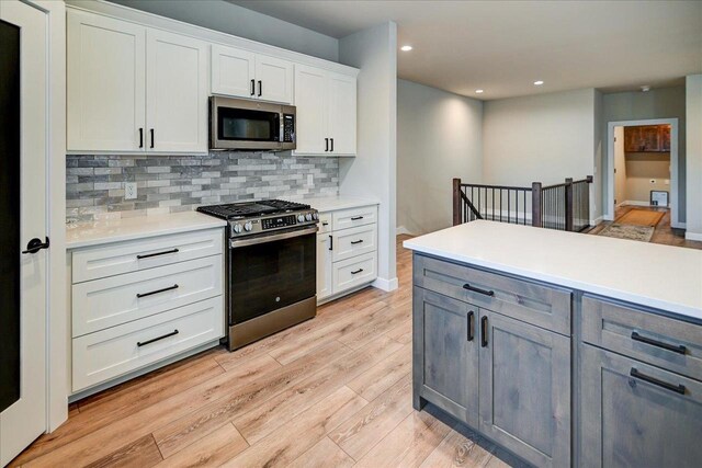 4021 Red Hawk Run, Black Earth, WI 53515 - kitchen with white cabinets, stainless steel appliances, backsplash, light countertops, and light wood-style flooring