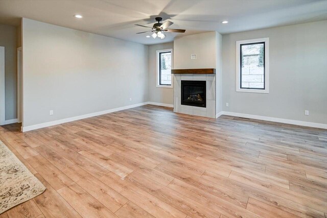 4021 Red Hawk Run, Black Earth, WI 53515 - unfurnished living room featuring a ceiling fan, a fireplace, a healthy amount of sunlight, and light wood-type flooring