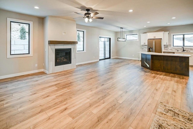 4021 Red Hawk Run, Black Earth, WI 53515 - unfurnished living room featuring a sink, ceiling fan, light wood finished floors, a fireplace, and baseboards
