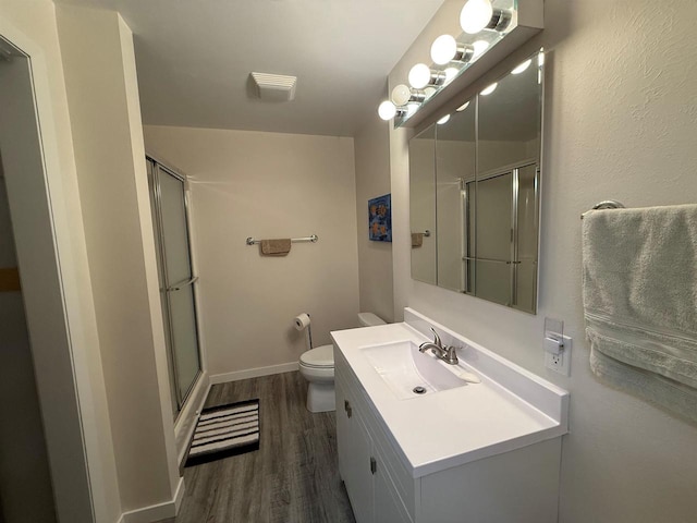 bathroom with a shower stall, vanity, toilet, baseboards, and wood finished floors