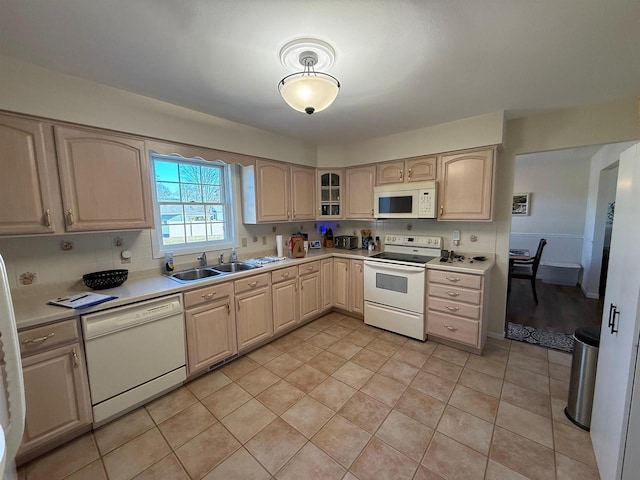 kitchen featuring a sink, light brown cabinets, glass insert cabinets, white appliances, and light countertops