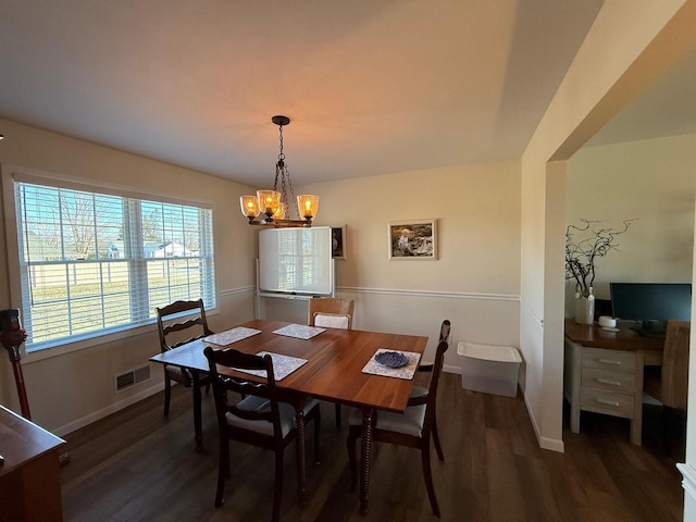 dining space with wood finished floors, visible vents, a chandelier, and baseboards
