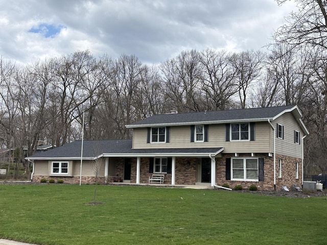 traditional-style home featuring a front lawn, covered porch, and brick siding