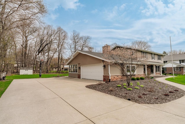 view of front facade featuring a chimney, brick siding, a front yard, concrete driveway, and an attached garage