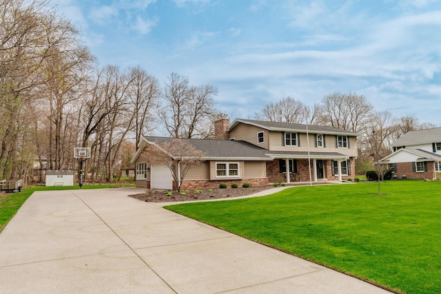 traditional-style house featuring a chimney, covered porch, driveway, a front lawn, and an attached garage