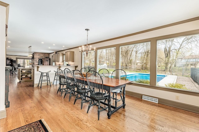 dining room featuring visible vents, ornamental molding, a notable chandelier, and light wood-style flooring